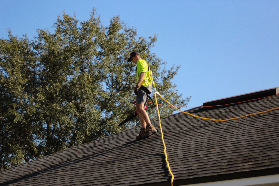 roofer in harness working on gutter repair