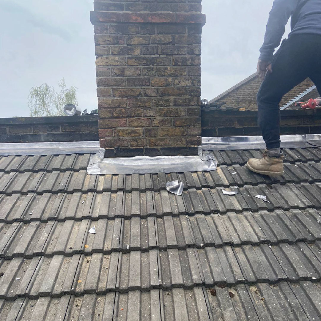 roofer carrying out chimney repairs on house