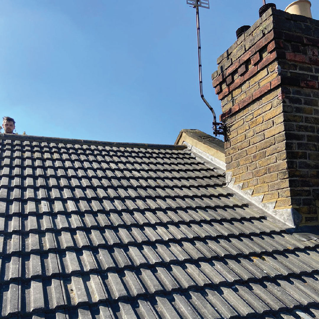 new masonry work on chimney with worker behind roof