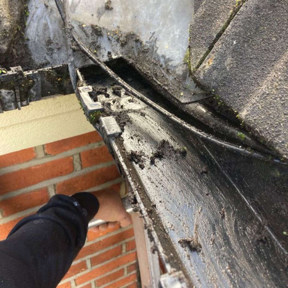 roofer cleaning dirty gutter