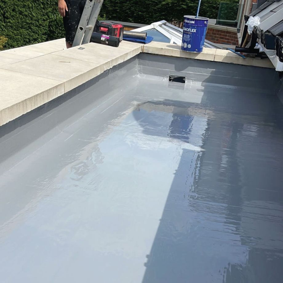 waterproofing installer on ladder overlooking flat roof